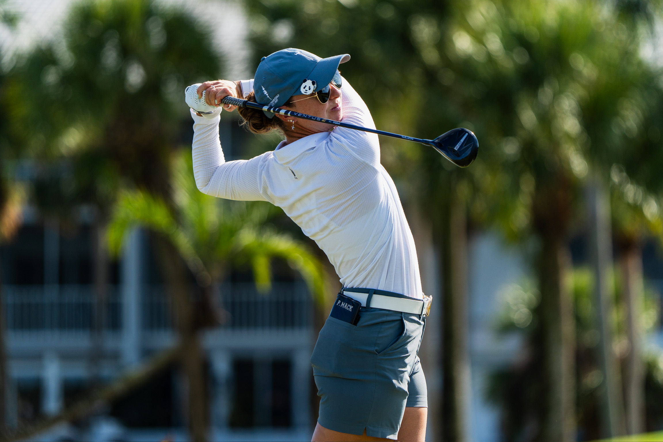 APN ambassador Polly driving on a palm-lined course