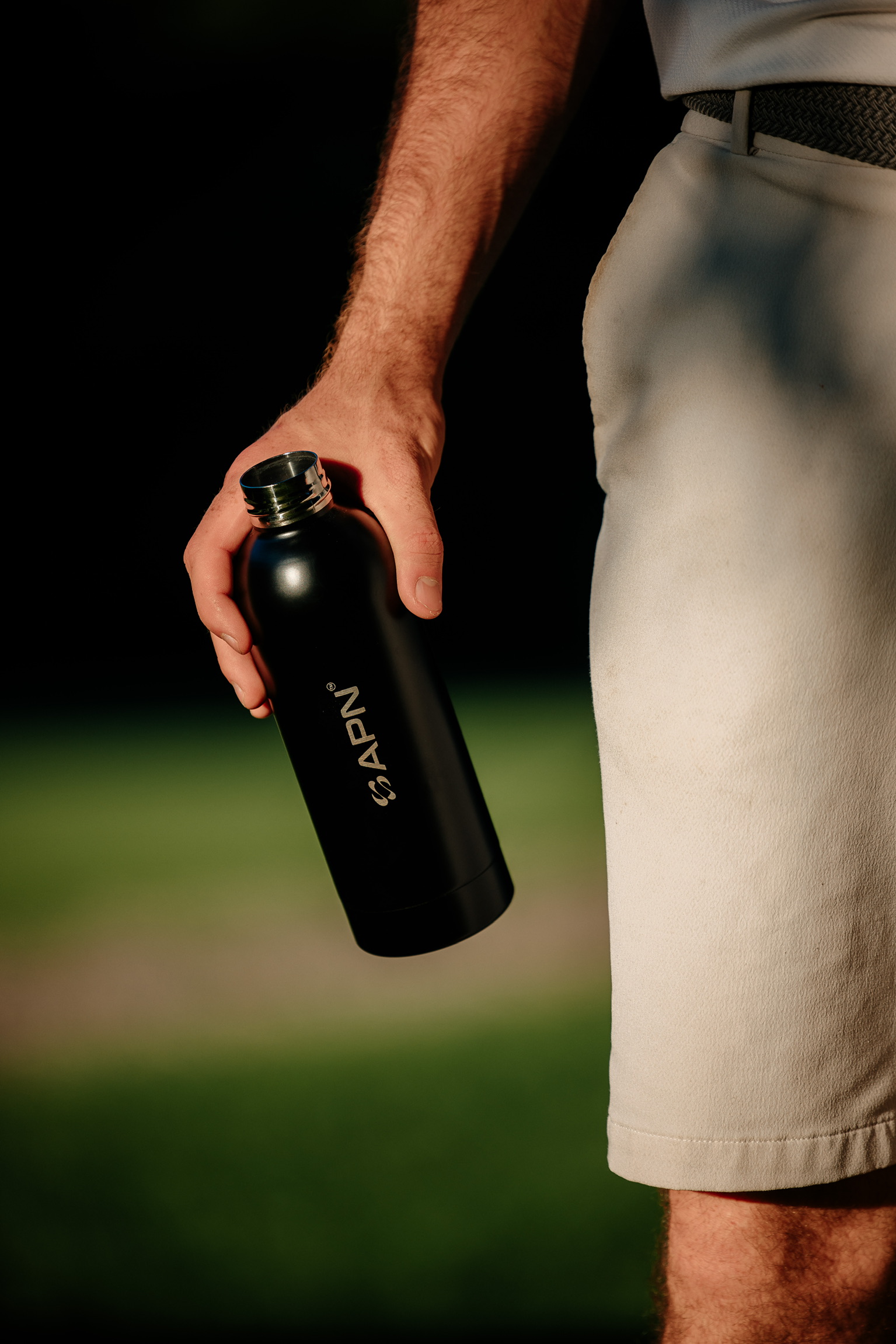 APN Water Bottle - Hand holding bottle on golf course