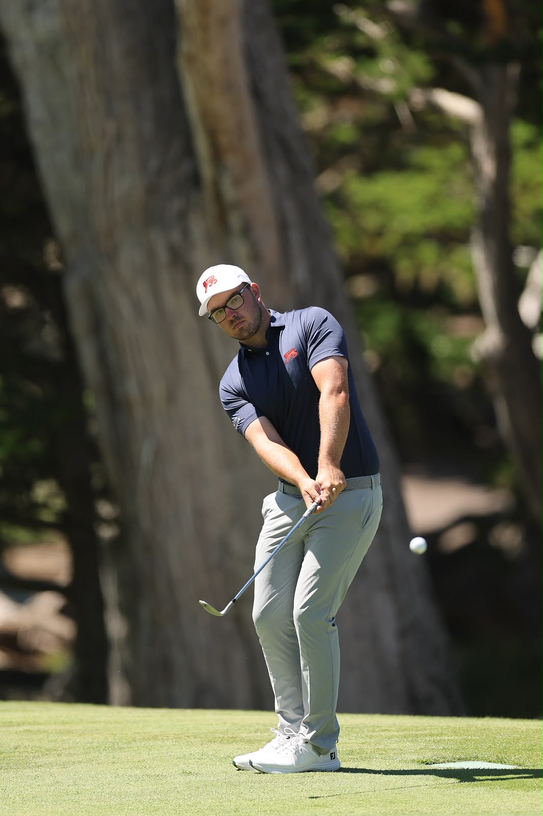 Eliot Baker chipping onto the green in focused concentration